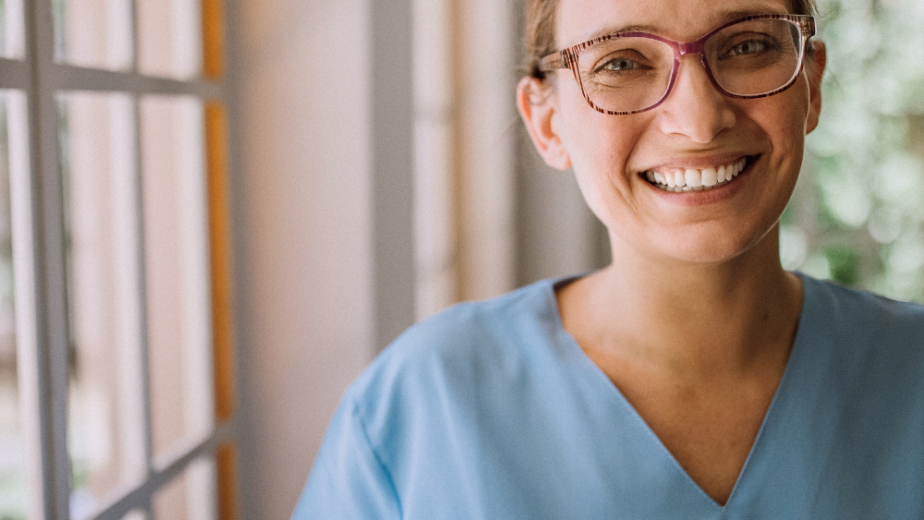 Professional healthcare worker smiling in blue scrubs in Ventura County California. Personalized Uniform Embroidery on medical scrubs