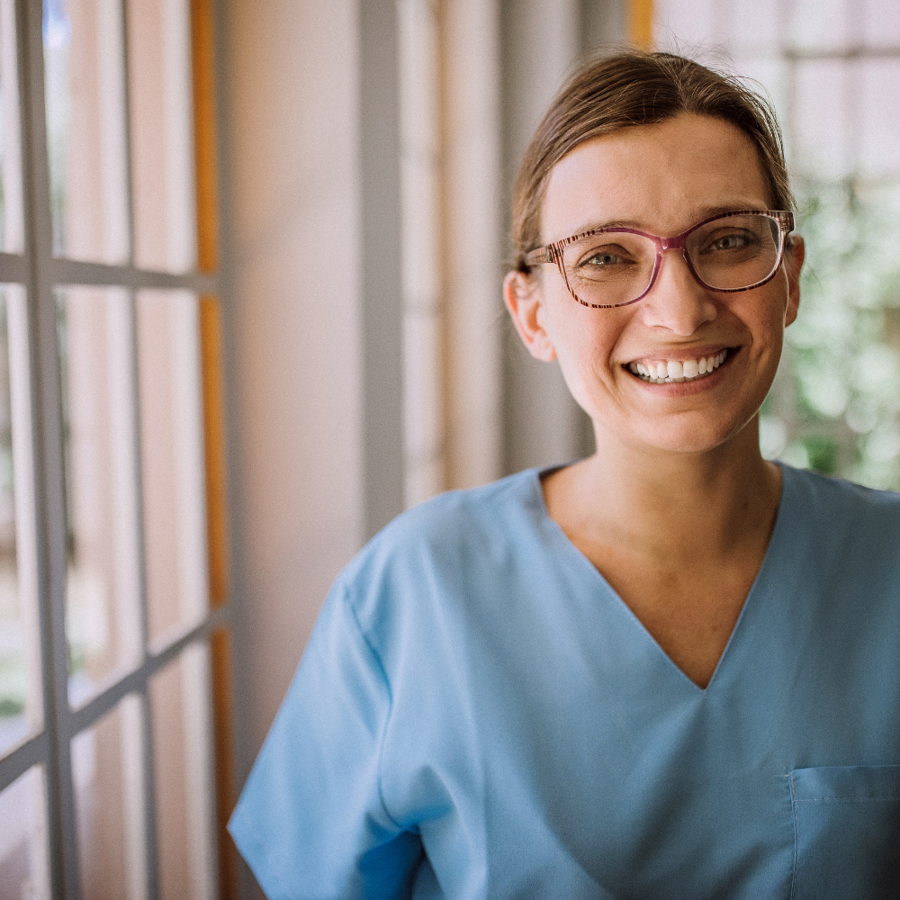 Professional healthcare worker smiling in blue scrubs in Ventura County California. Personalized Uniform Embroidery on medical scrubs
