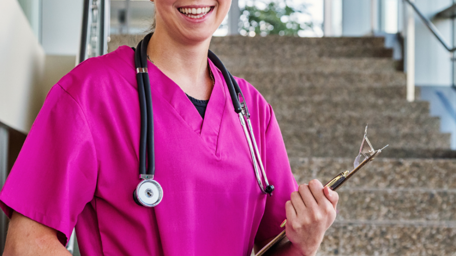 Nurse wearing pink scrubs standing on stairs in a Ventura County California medical setting.
