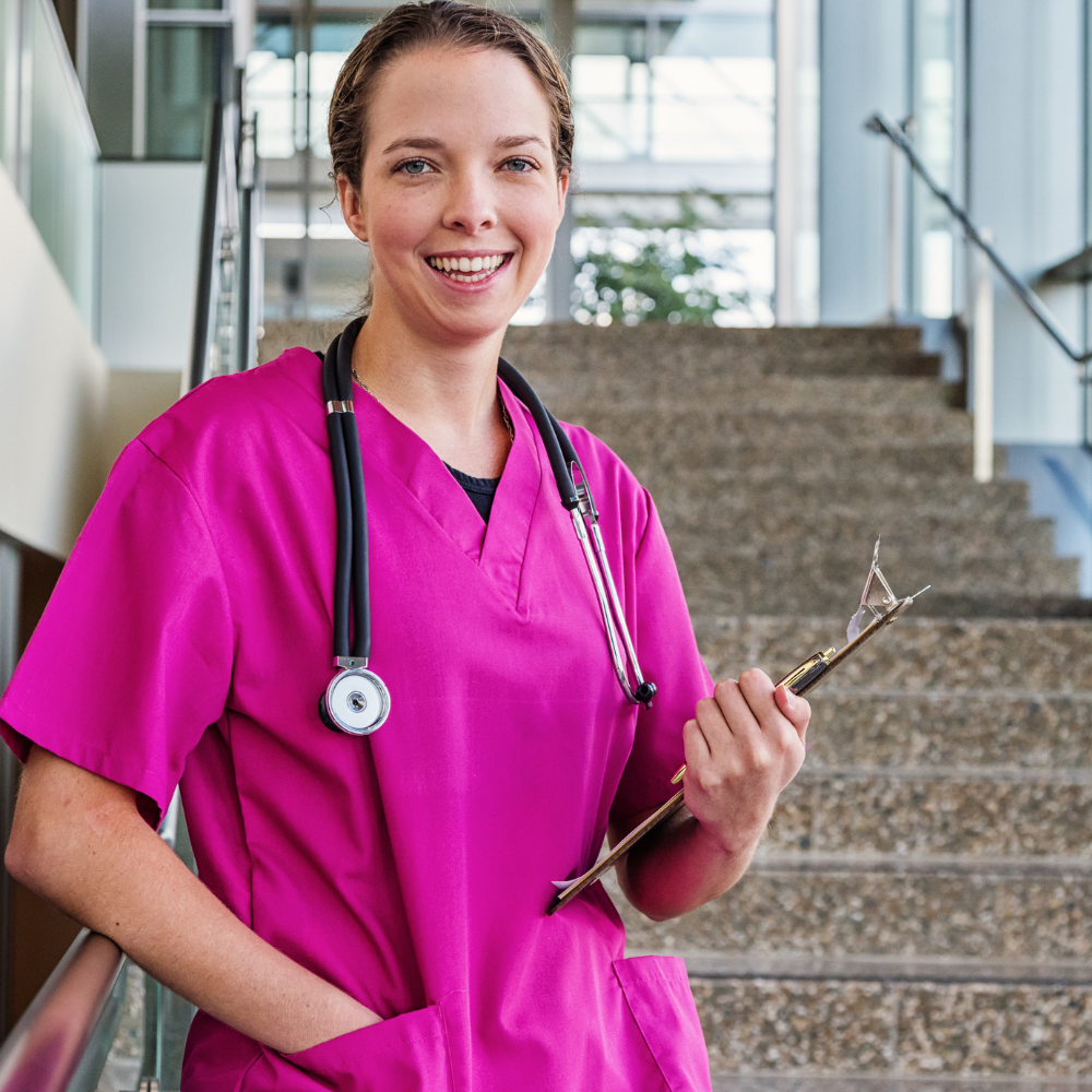 Nurse wearing pink scrubs standing on stairs in a Ventura County California medical setting.