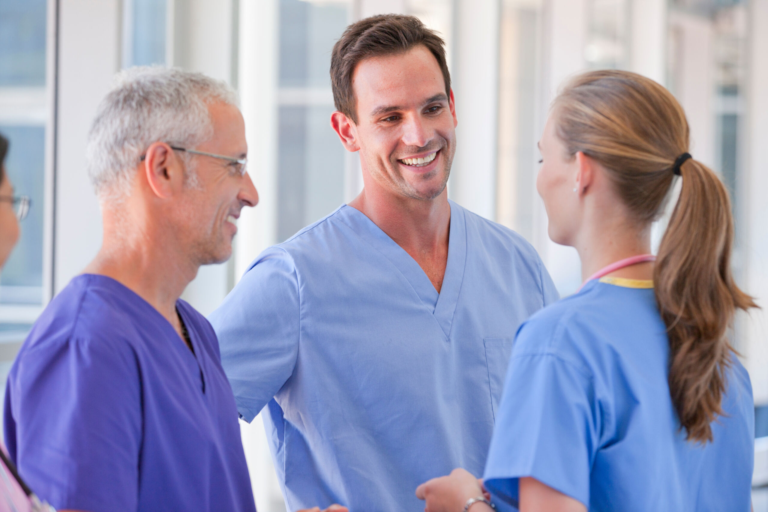 Doctors and nurses speaking together in a clinical work environment.